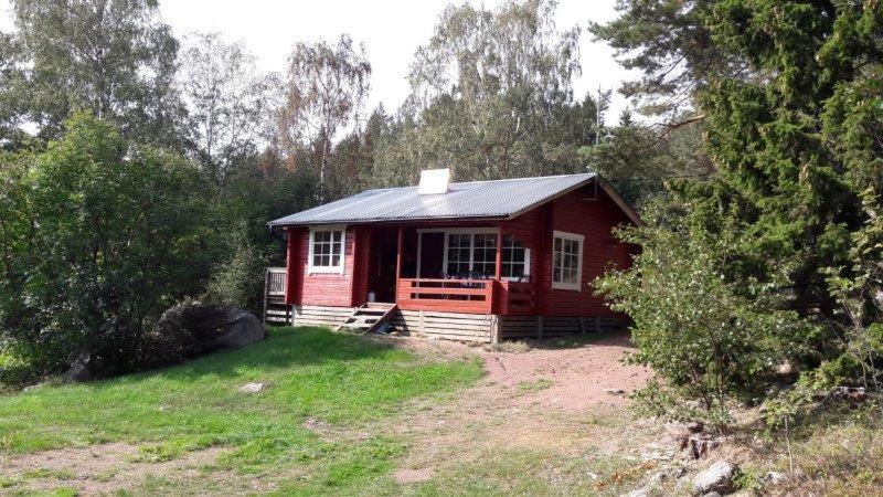 a small red cabin in the middle of a field at Mellangårds stugor - Stockstugan in Föglö