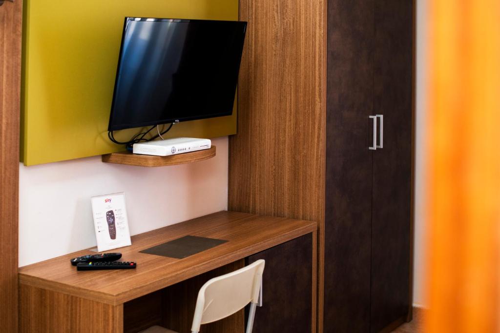 a room with a desk with a television on a wall at Gu Hotel in Guidonia