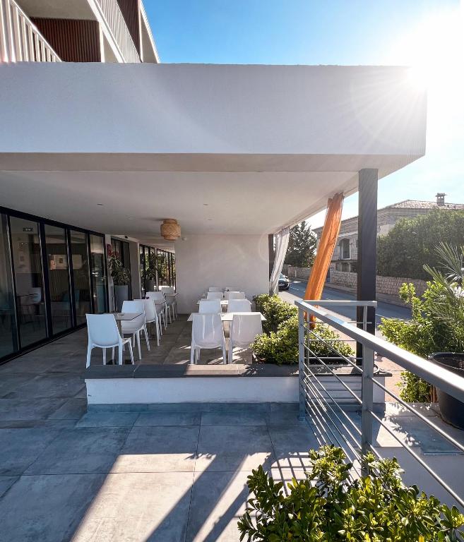 a restaurant with white tables and chairs on a balcony at Hotel l'Isolella in Porticcio