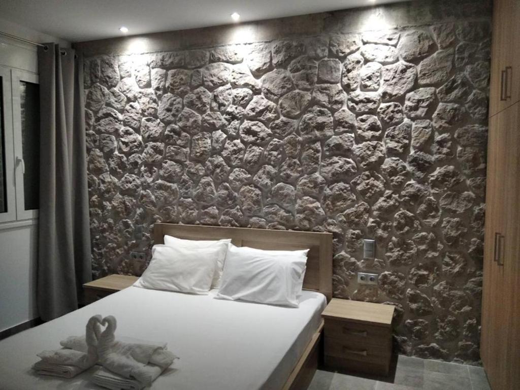 1 dormitorio con 1 cama y pared de piedra en Estia - Brand new apartment in Ermioni Village, en Ermioni