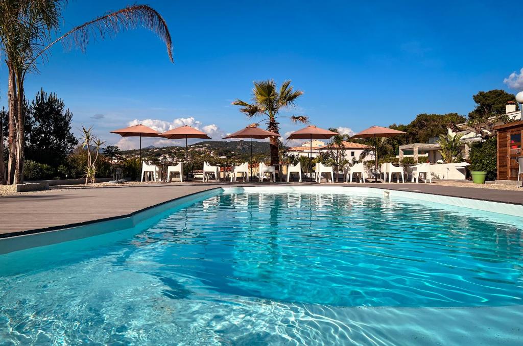 a swimming pool with chairs and umbrellas in a resort at Hotel l'Isolella in Porticcio