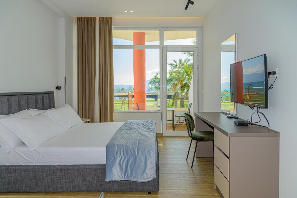 una camera con letto e scrivania con TV di Palm Side Hotel a Vlorë