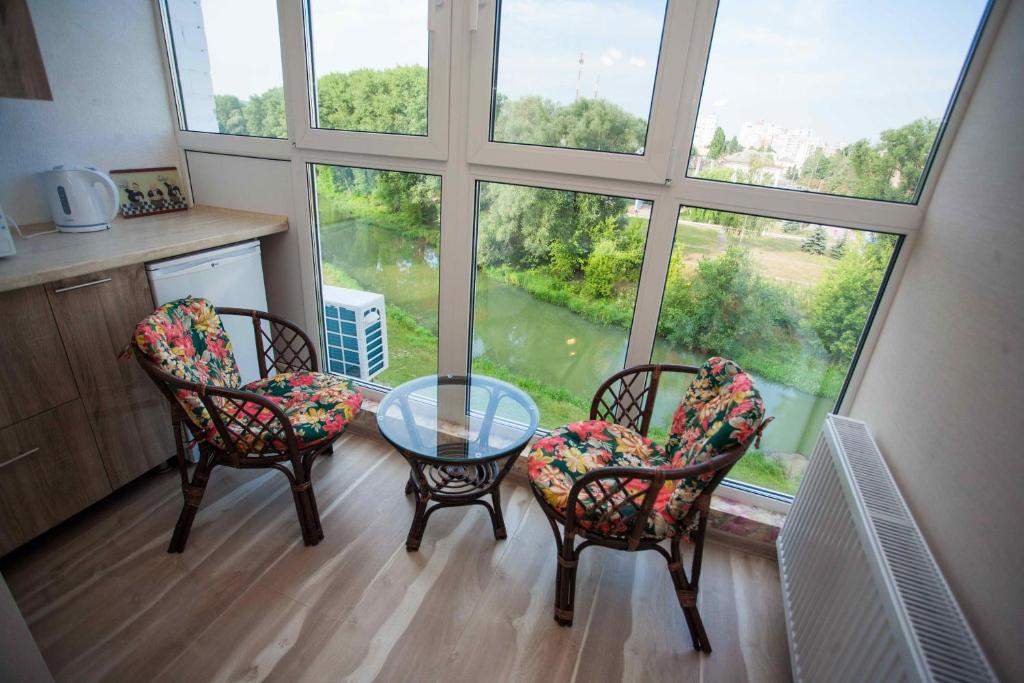 um quarto com três cadeiras e uma mesa de vidro em frente a uma janela em Molex Apartments 2 em Chernigov