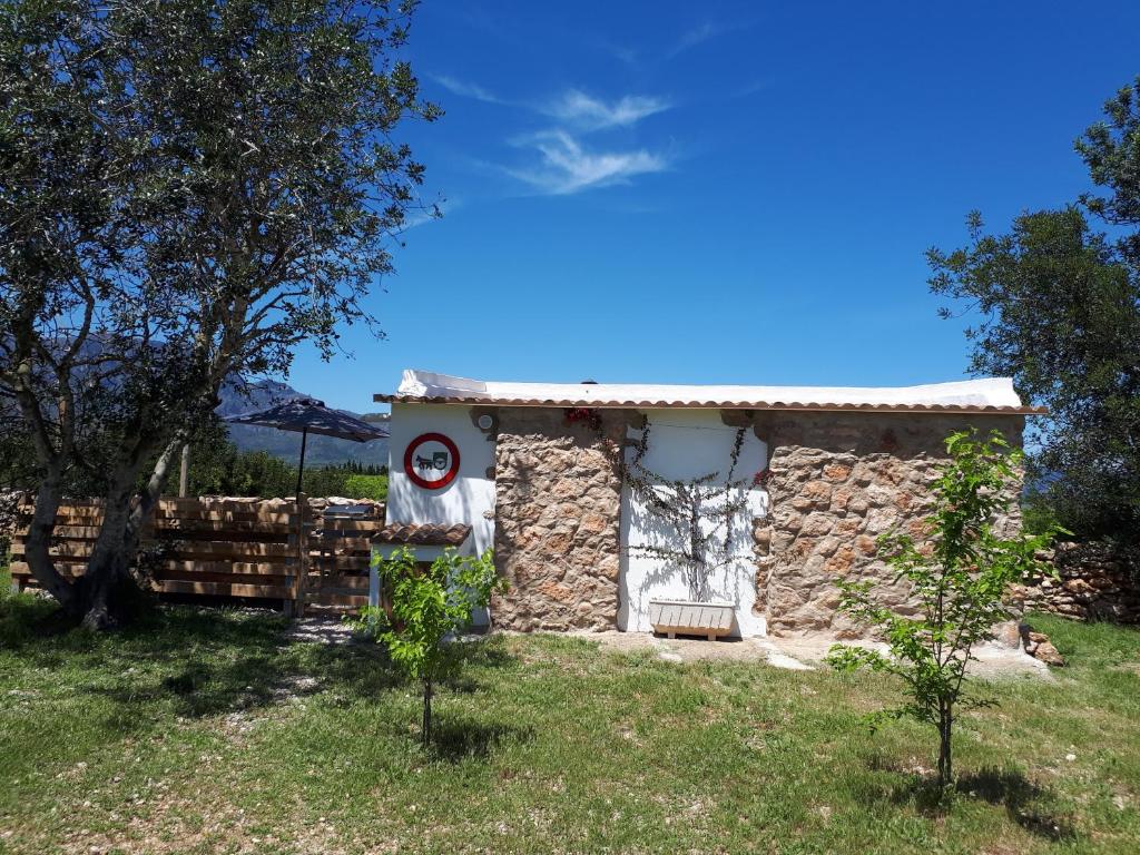 una pequeña casa de piedra en un campo con una valla en El Establo en Roquetas