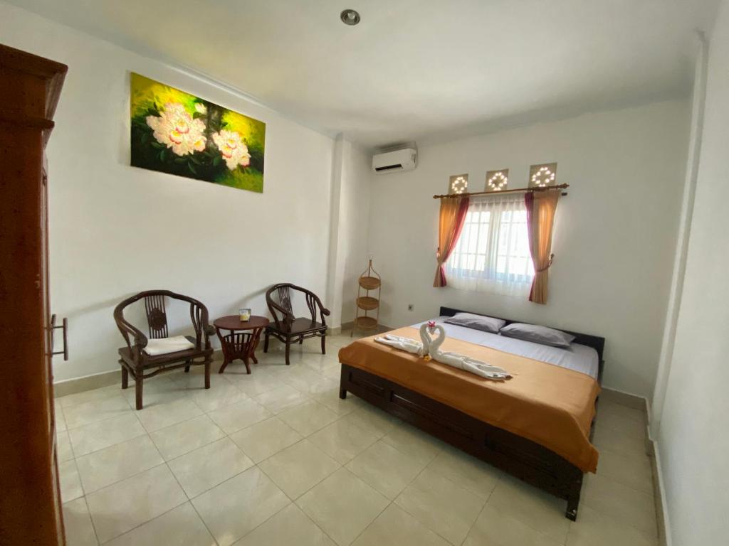 a bedroom with a bed and a table and chairs at Pondok Mimba in Padangbai