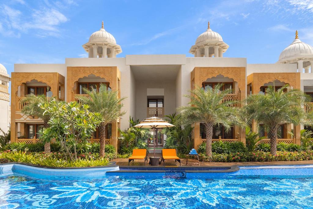 a resort with a swimming pool in front of a building at Kaldan Samudhra Palace, a Palace by the Sea in Mahabalipuram