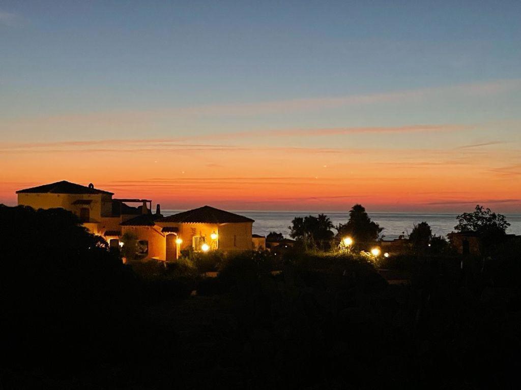 una vista de una casa con la puesta de sol en el fondo en Casa vacanze Calarossa (Sardegna), en Isola Rossa