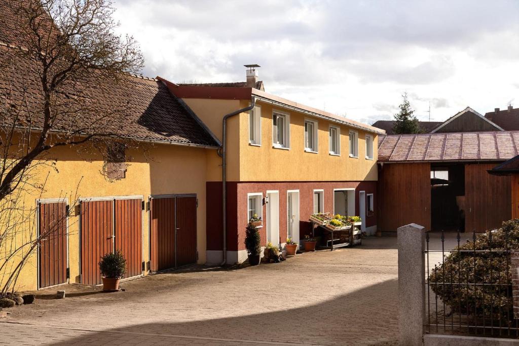 ein gelbes und orangefarbenes Haus mit einem Zaun daneben. in der Unterkunft Gästezimmer/Appartement Familie John in Veitsbronn