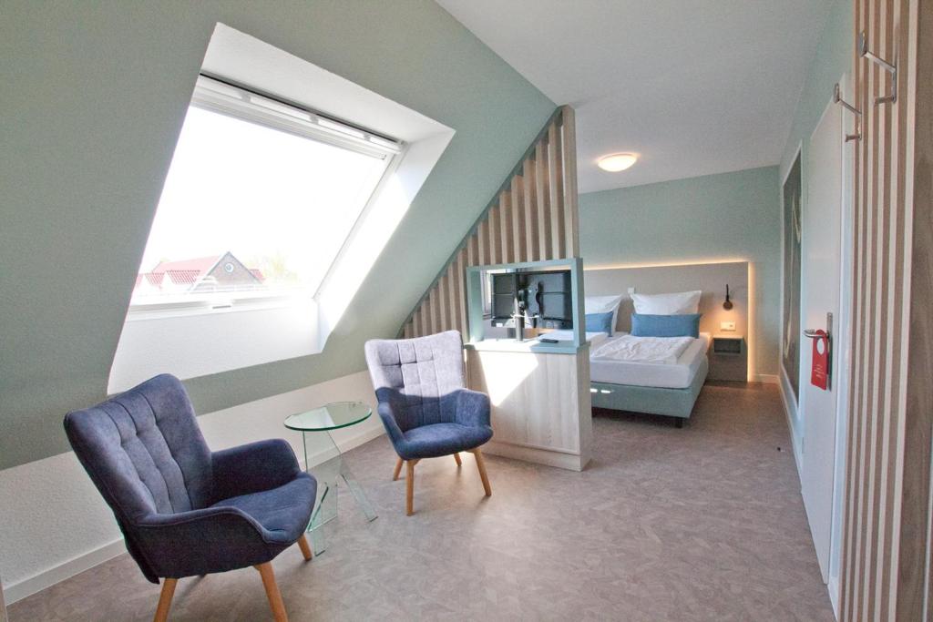 a bedroom with a bed and two chairs and a table at Hotel Garni Goldener Anker in Greetsiel