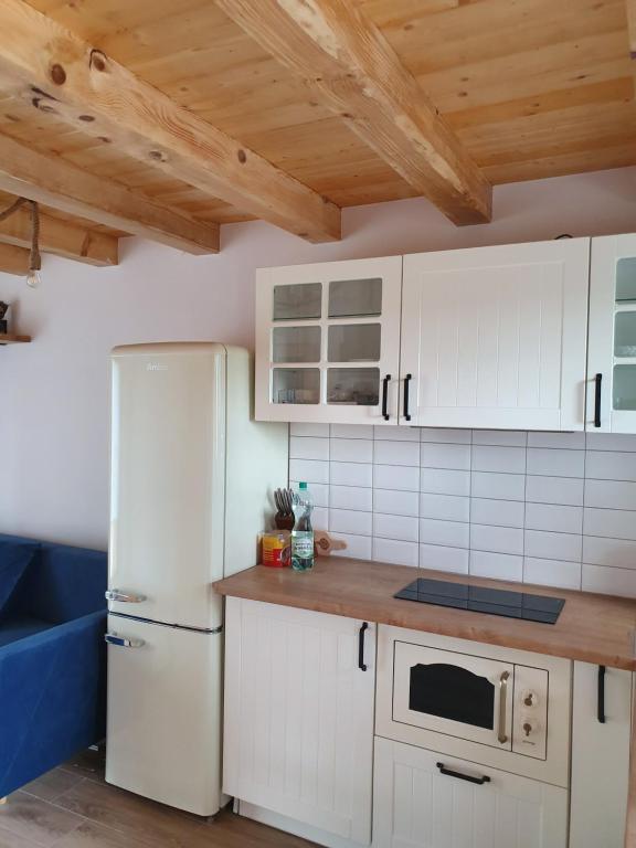 una cocina con electrodomésticos blancos y techos de madera. en Oleksowiczówka en Zborowice