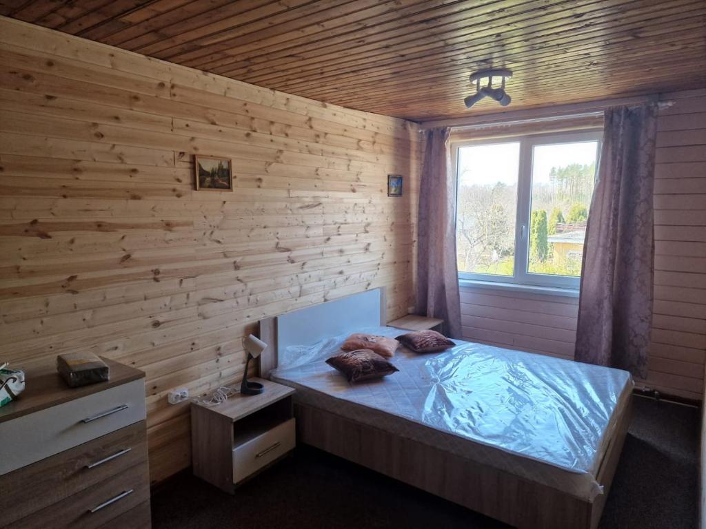 een slaapkamer met een bed in een houten muur bij Ķīšupe 2 in Saulkrasti