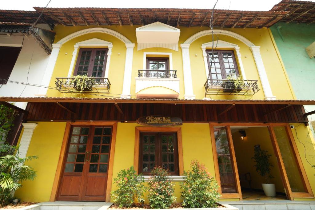 ein gelbes und weißes Haus mit Fenstern und Türen in der Unterkunft THE SUNSET BAY in Fort Kochi