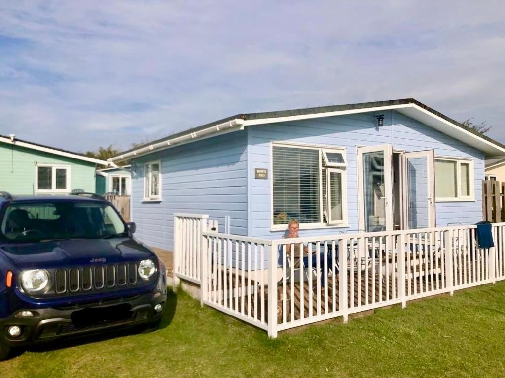 a jeep parked in front of a blue house at Holiday Chalet at Gwithian Sands in Cornwall in Gwithian