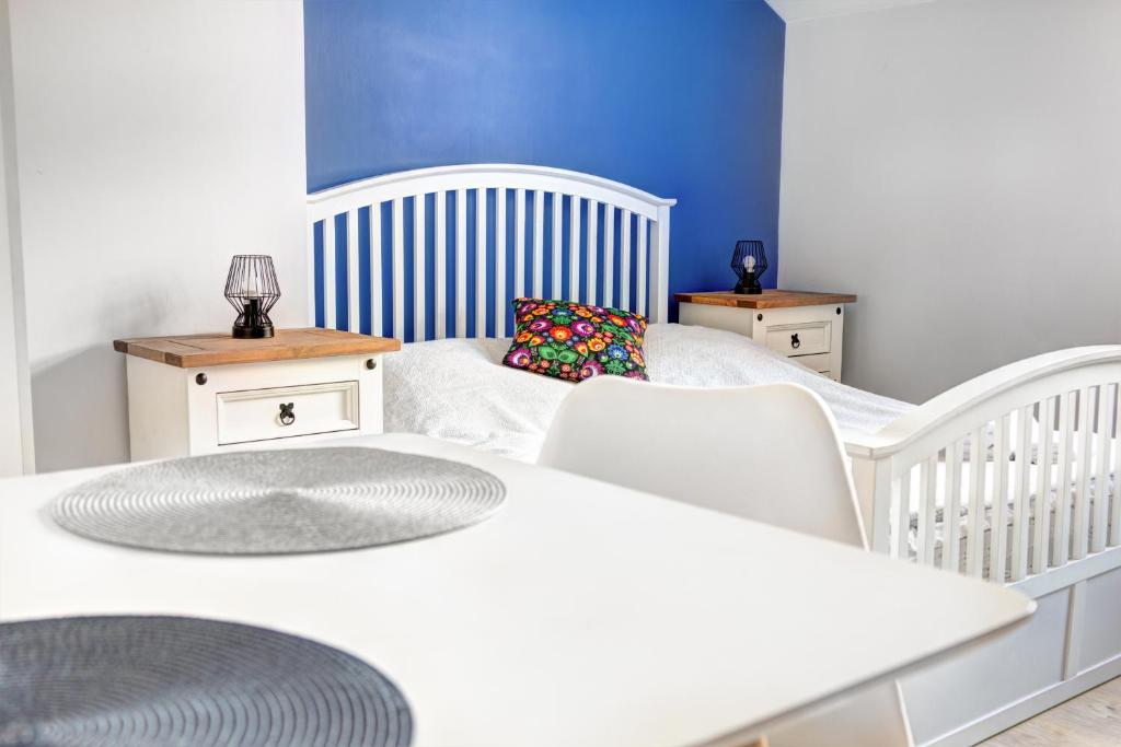 - un lit bébé blanc dans une chambre avec un lit et deux tables dans l'établissement Rentimi - Apartament Skandynawski 2, à Krynica-Zdrój