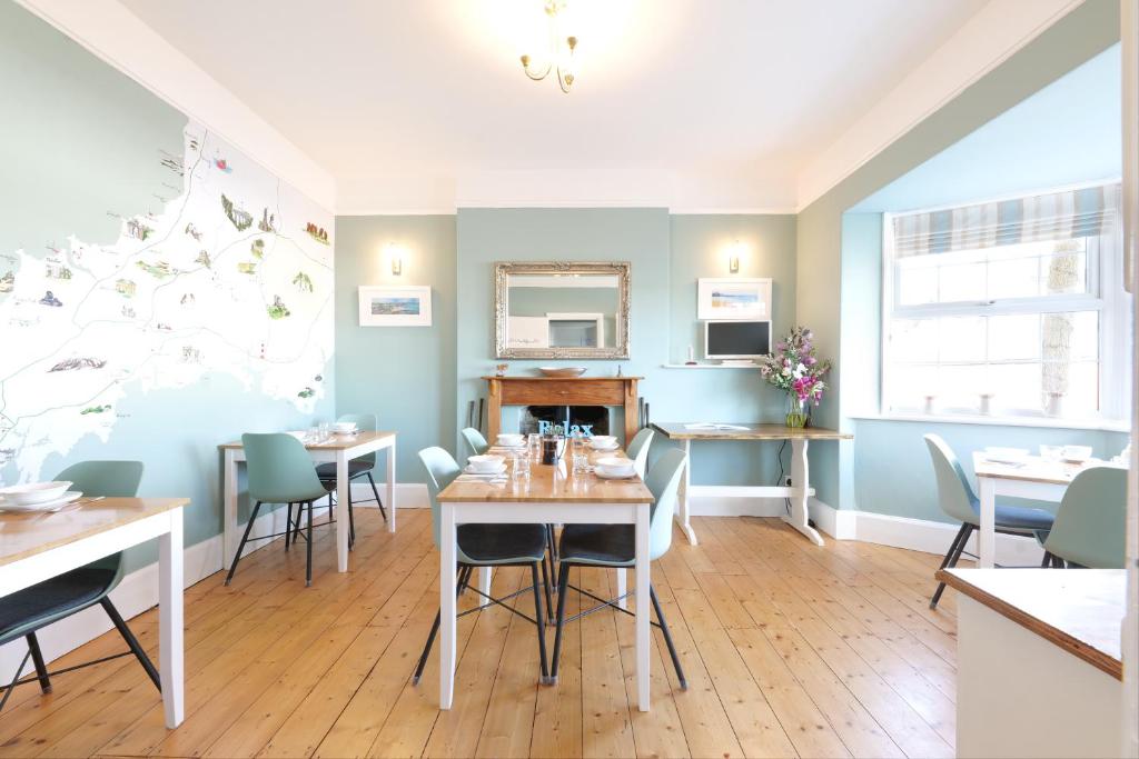 een eetkamer met tafels en stoelen en een spiegel bij Tee-Side Guest House in Bude