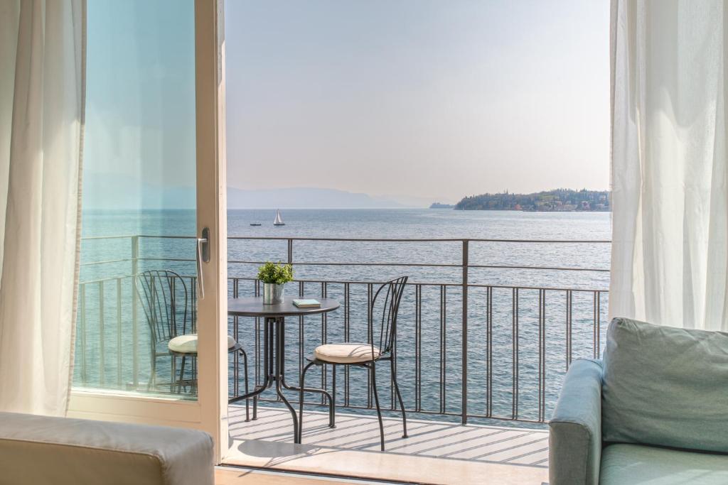 a balcony with a table and chairs and a view of the water at Luxury Lake View Apartments in Salò