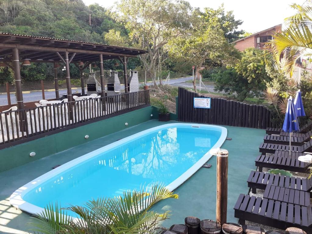 a swimming pool with two chairs next to it at Hotel Bela Onda in Bombinhas