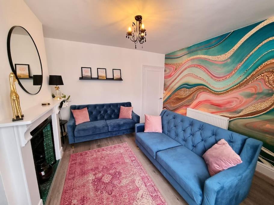 a living room with two blue couches and a mural at Beautiful & Vibrant City Centre House in Canterbury