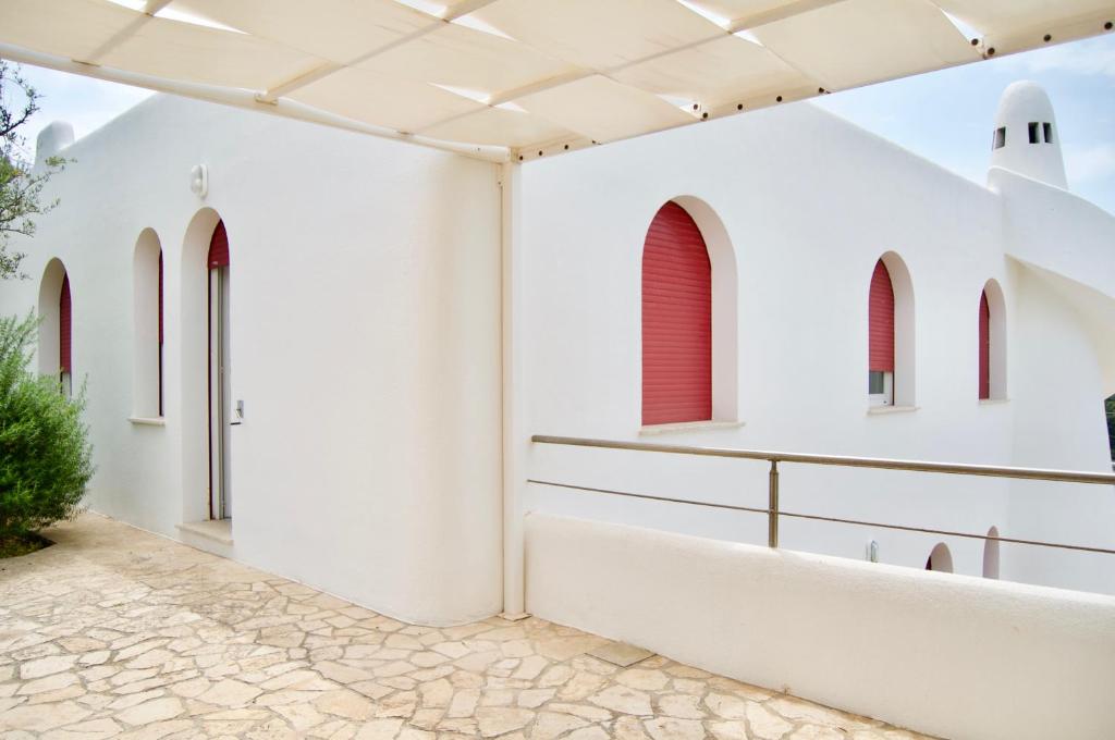 - une vue extérieure sur un bâtiment blanc doté de fenêtres rouges dans l'établissement Appartamento BelMar, à Marina San Gregorio