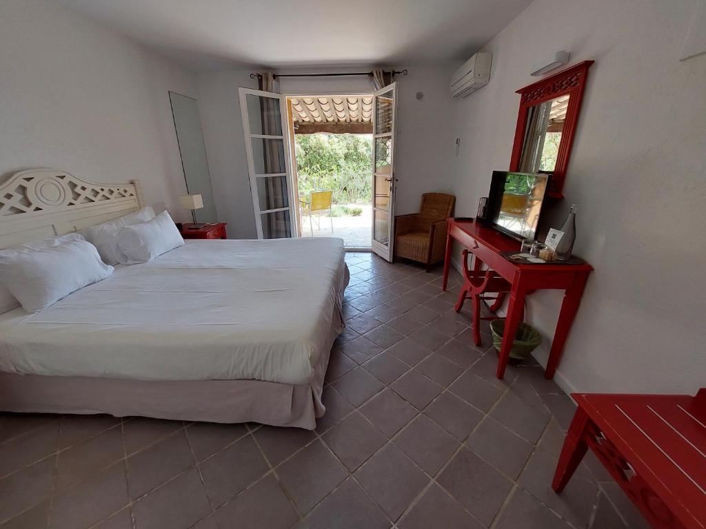 a bedroom with a bed and a desk and a television at Hôtel les Bouis - Vue mer in Saint-Tropez
