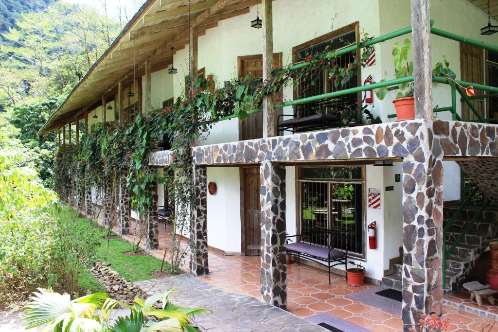 un edificio con un porche con plantas. en Bosque de Paz Reserva Biologica en Toro Amarillo