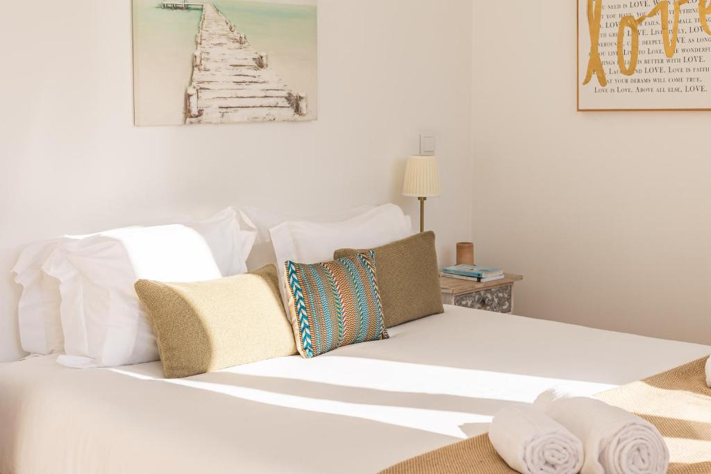 ein weißes Bett mit Kissen und Handtüchern darauf in der Unterkunft Bright Tailor Made Flat With a View in Estrela in Lissabon