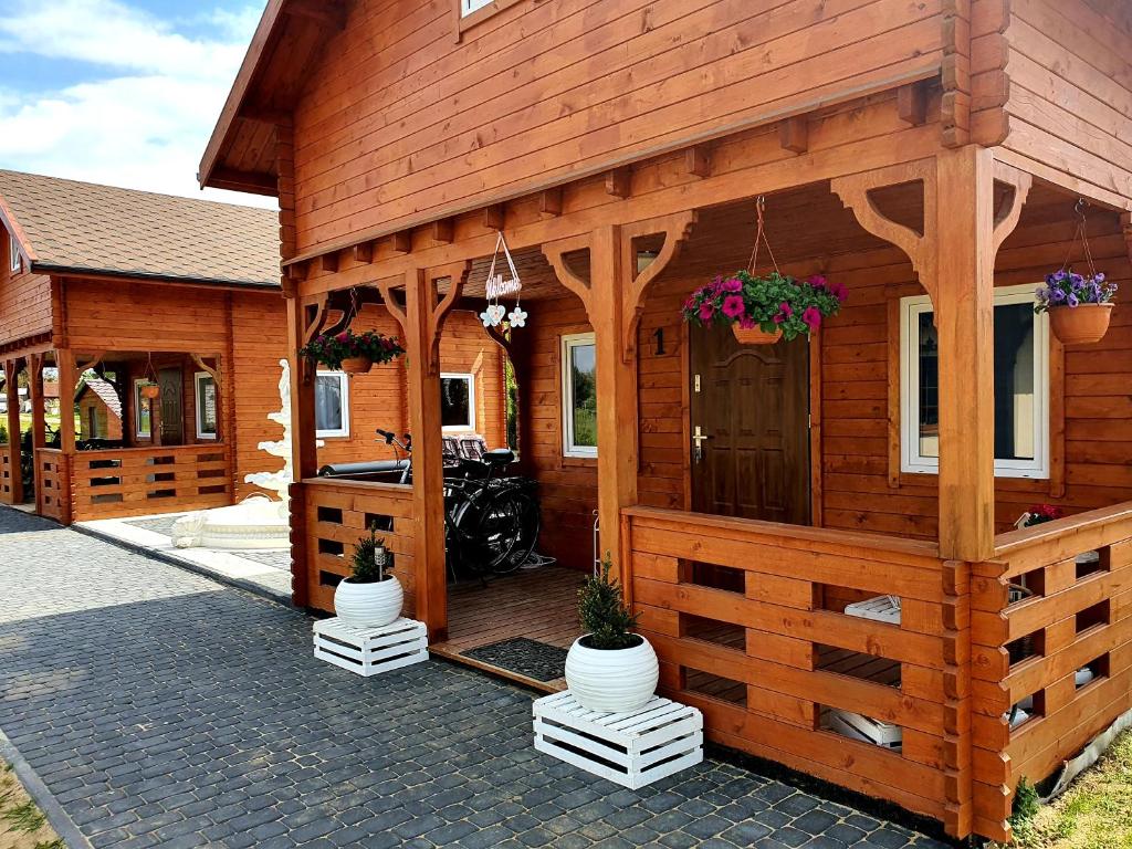 a wooden cabin with a porch and a motorcycle parked outside at Noclegi "LAS WYPAS" 2 Domki drewniane całoroczne, oraz 1 Apartament dla dwojga - wynajem in Trzcianka