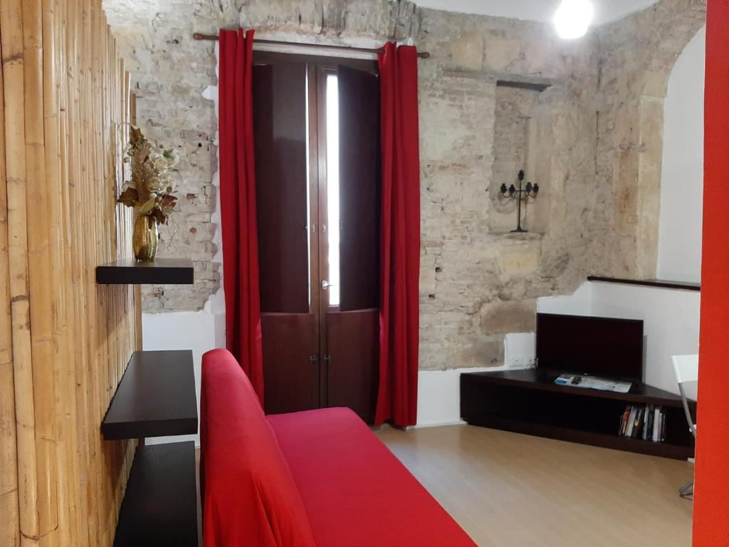 un soggiorno con tende rosse e un divano rosso di Le Torri a Cagliari