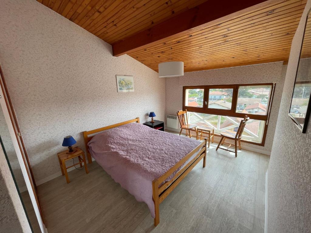 a bedroom with a bed and a table and a window at L&#39;Abri Côtier in Mimizan