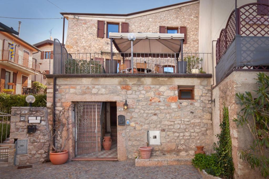 a stone house with a balcony and a patio at Casa Delle Stelle in Torri del Benaco