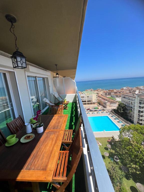 einen Balkon mit einem Holztisch und Meerblick in der Unterkunft Apartamento Carihuela Torremolinos in Torremolinos