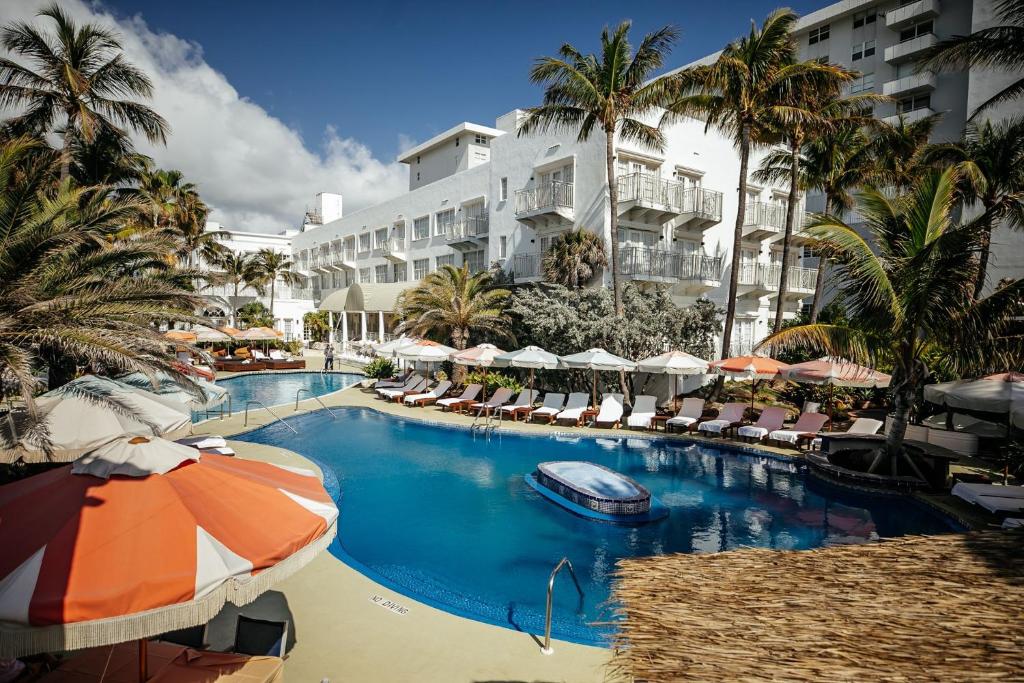 una grande piscina con ombrelloni e una barca di The Savoy Hotel & Beach Club a Miami Beach