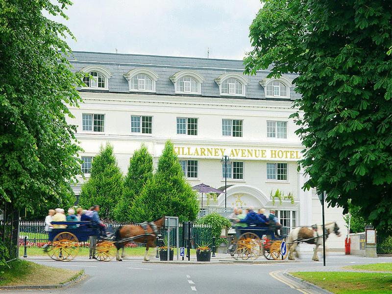 uma carruagem puxada por cavalos em frente a um hotel em Killarney Avenue em Killarney