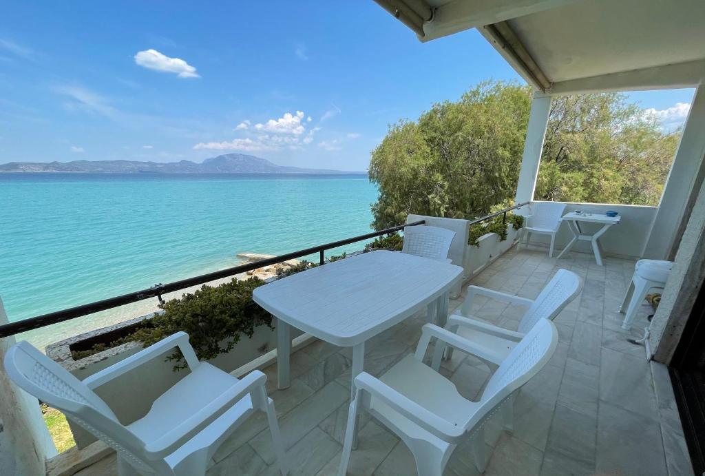 Biały stół i krzesła na balkonie z widokiem na ocean w obiekcie Stunning Beachfront Apartment Strátos w mieście Nerántza