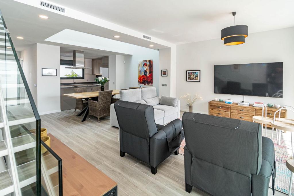 ein Wohnzimmer mit 2 Stühlen, einem Sofa und einem TV in der Unterkunft LMT46- Spacious townhouse modern style in Estepona