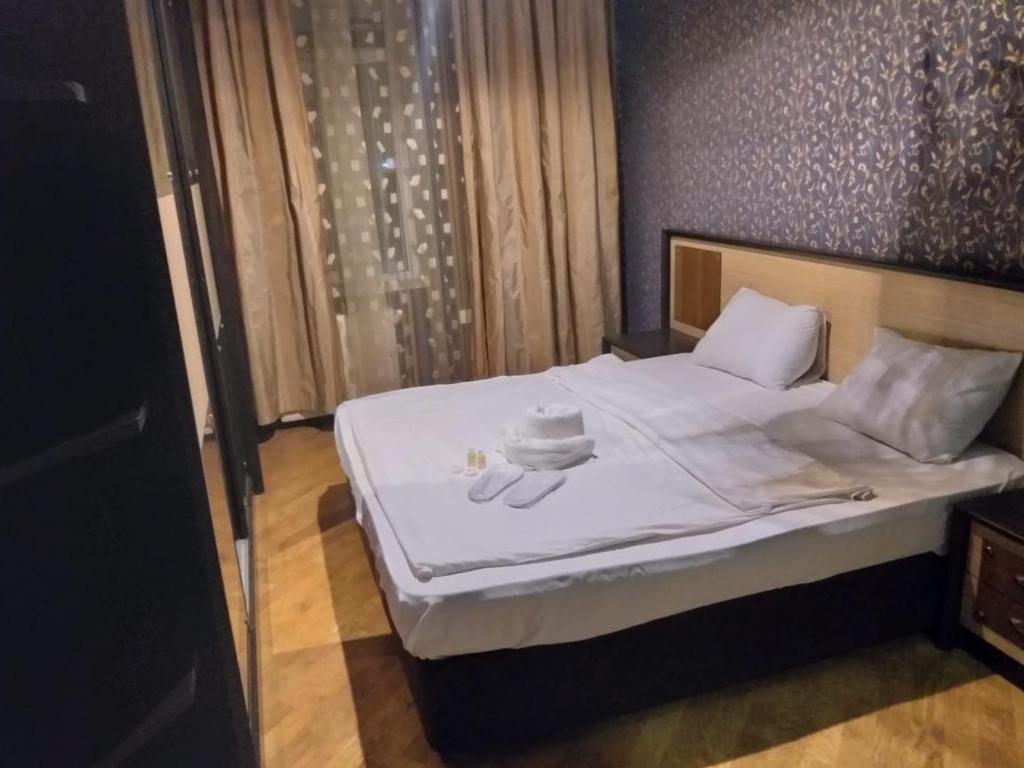 uma cama com lençóis brancos e toalhas em Apartament caspian plaza em Baku