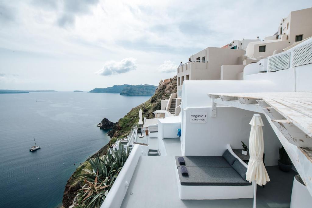 a view of the ocean from the side of a white building at Virginia's Cave Villas in Oia
