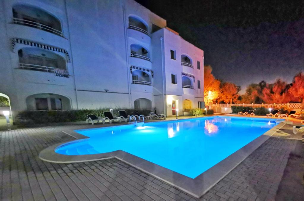 een groot zwembad voor een gebouw 's nachts bij Relax Home in La Caletta