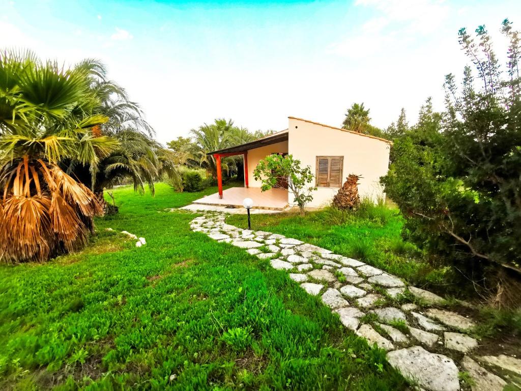 uma casa no meio de um campo verde com um caminho em L'oasi nello Zingaro em Scopello