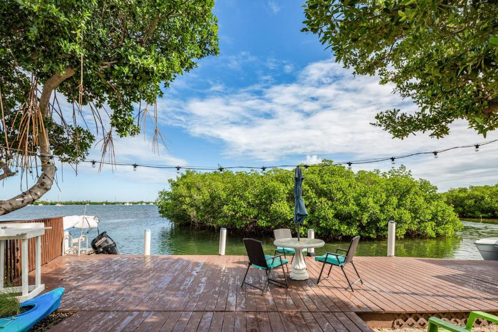 a wooden deck with chairs and a table next to the water at Casa Isabelle by Brightwild in Key West