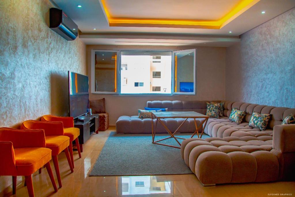 un salon avec un canapé, des fauteuils et une télévision dans l'établissement Islane vue piscine, à Agadir