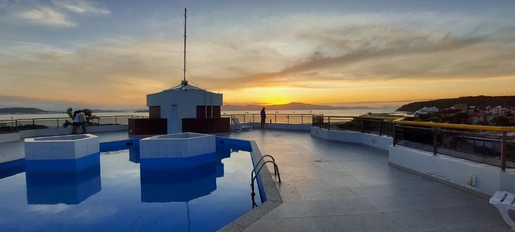 una piscina en la parte superior de un edificio con puesta de sol en Apartamento Guarapuvu, en Florianópolis