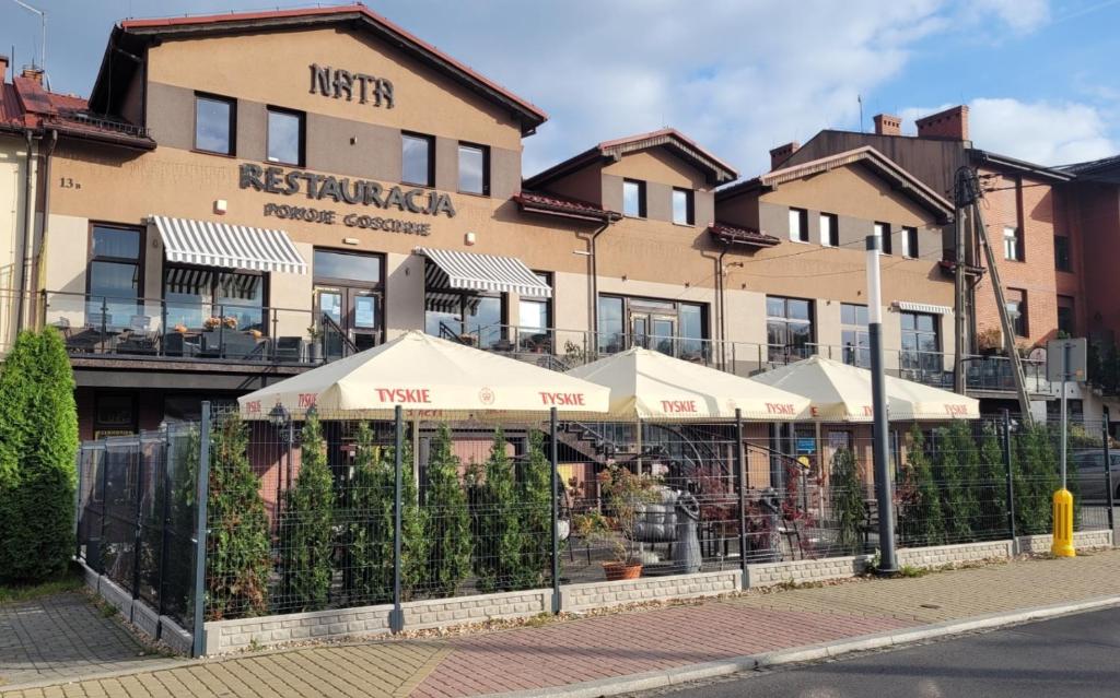 ein Restaurant mit Sonnenschirmen vor einem Gebäude in der Unterkunft Nata Pokoje Gościnne Restauracja in Libiąż