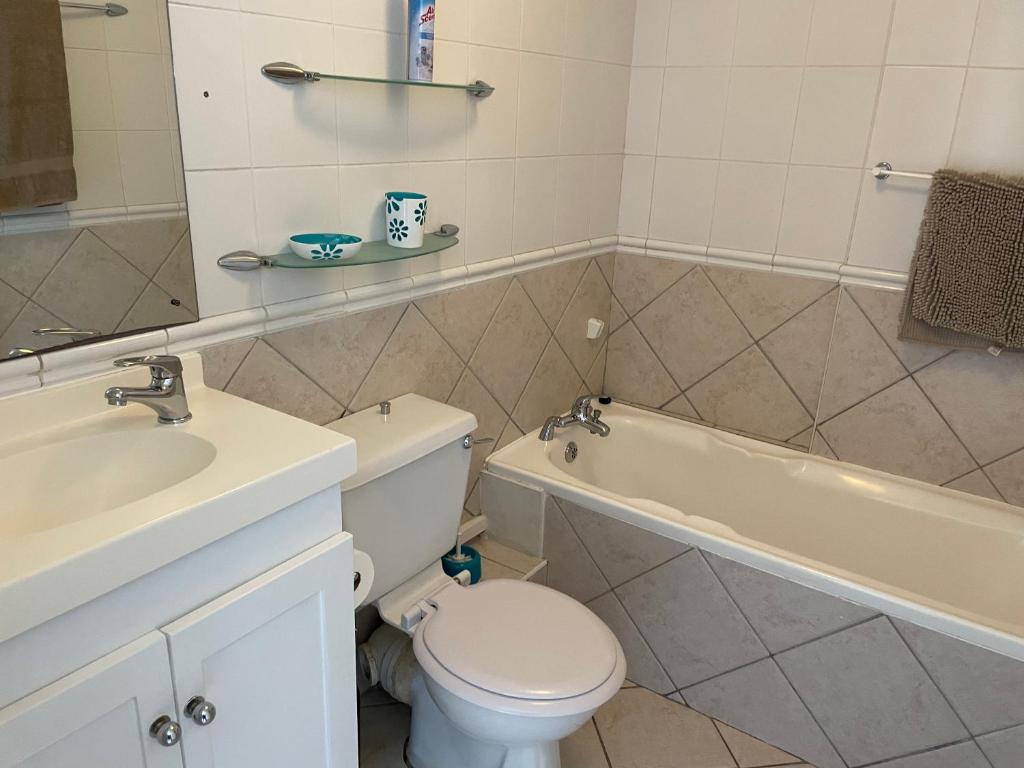 a bathroom with a toilet and a tub and a sink at Ocean View B1001 in Bloubergstrand