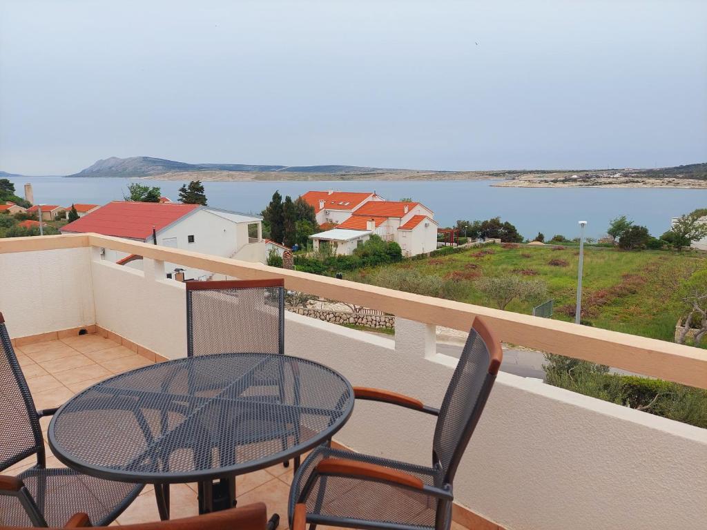 a balcony with a table and chairs and a view of the water at Apartments Donadic I, Caska in Novalja