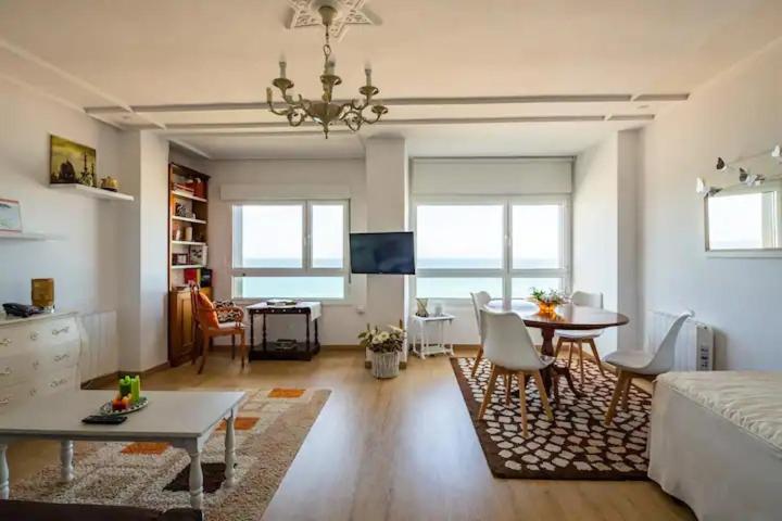 ein Wohnzimmer mit einem Sofa und einem Tisch in der Unterkunft Apartamento Ezcurdia 22 Playa de San Lorenzo primera línea in Gijón