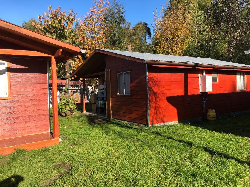 una piccola stalla con un edificio rosso nell'erba di Cabañas melinka a Licán Ray