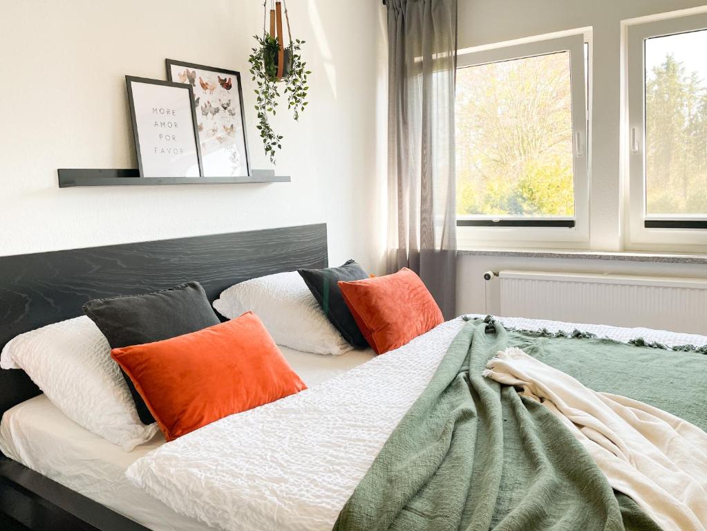 um quarto com uma cama com almofadas laranja e branca em Ferienhof Bannick em Bistensee