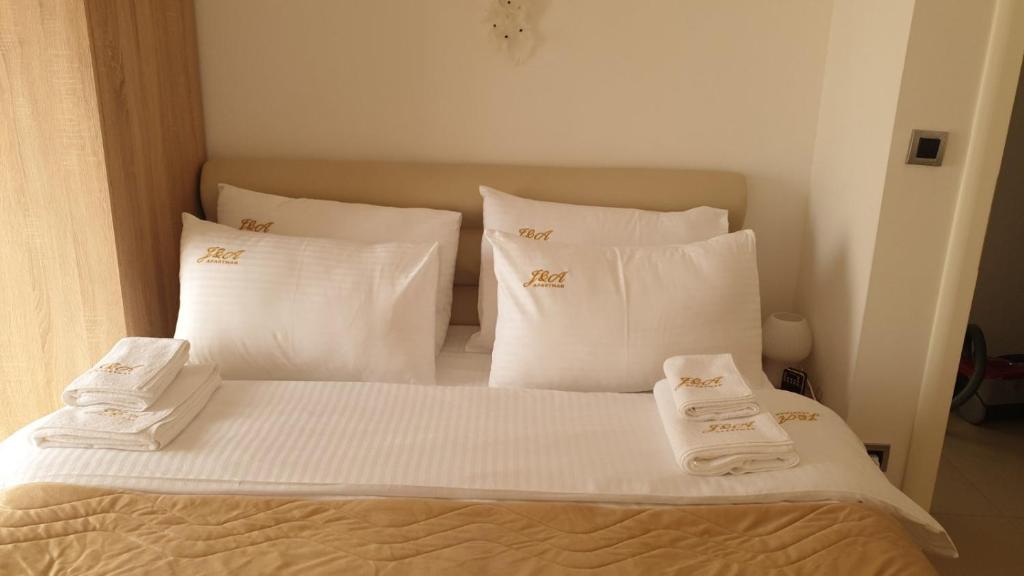 - un lit avec des oreillers et des serviettes blancs dans l'établissement J&A Apartman, à Jagodina