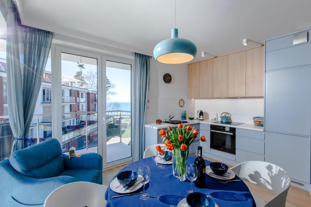 - une cuisine et un salon avec une table fleurie dans l'établissement Apartament z basenem "Przy Morzu", à Rewal